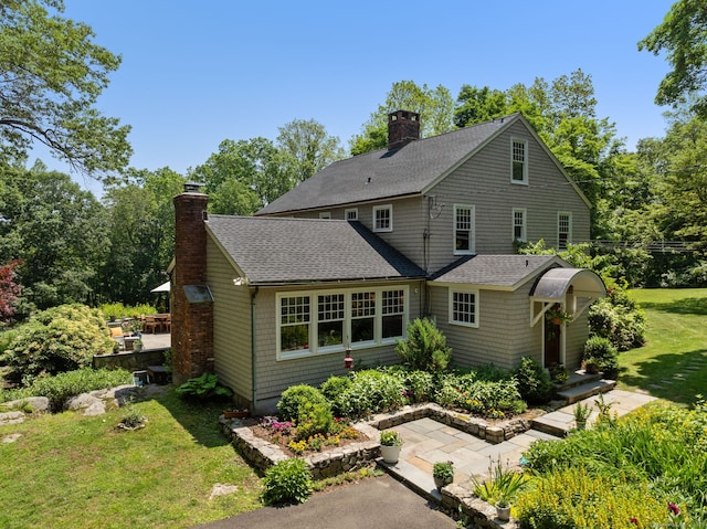 56 Turtleback Rd, Wilton, CT 06897 - rear view of house with a chimney, a shingled roof, and a lawn