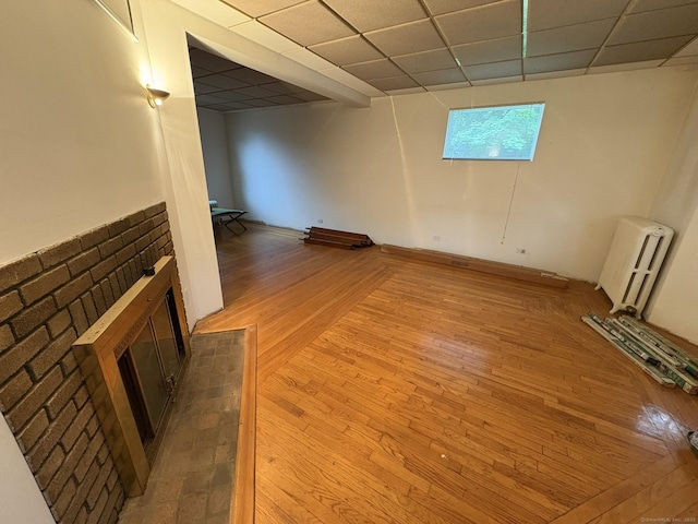 91 Hyde St, New Haven, CT 06512 - empty room featuring radiator, a brick fireplace, light wood-style floors, and a drop ceiling