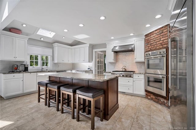 26 Ruscoe Rd, Wilton, CT 06897 - kitchen with stainless steel appliances, a center island, tasteful backsplash, white cabinetry, and range hood