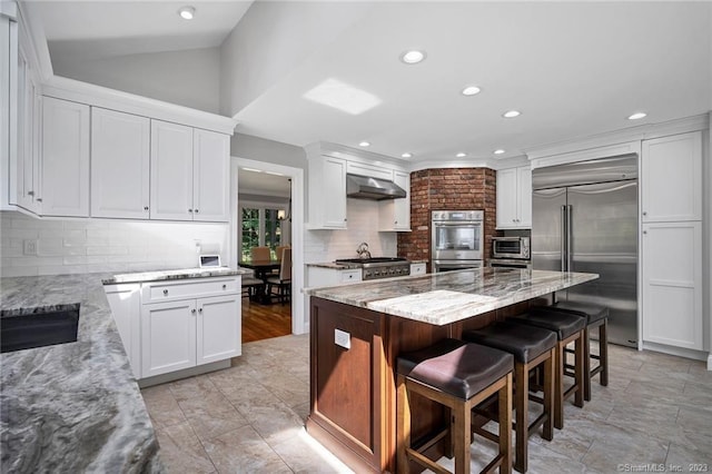 26 Ruscoe Rd, Wilton, CT 06897 - kitchen featuring appliances with stainless steel finishes, decorative backsplash, light stone counters, white cabinets, and recessed lighting