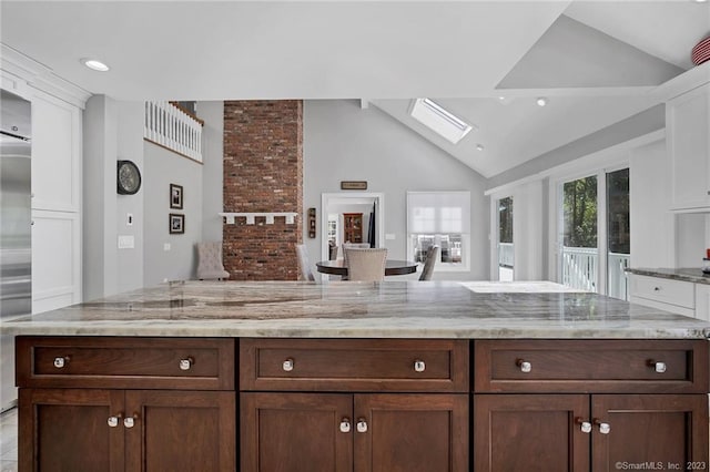 26 Ruscoe Rd, Wilton, CT 06897 - kitchen featuring vaulted ceiling, a skylight, white cabinets, light stone countertops, and dark brown cabinets
