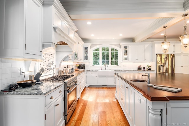 kitchen with stainless steel appliances, light wood-style floors, white cabinets, tasteful backsplash, and glass insert cabinets