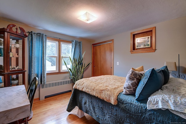 47 Hoffman Rd, Manchester, CT 06042 - bedroom with radiator heating unit, light wood-type flooring, a textured ceiling, and a closet