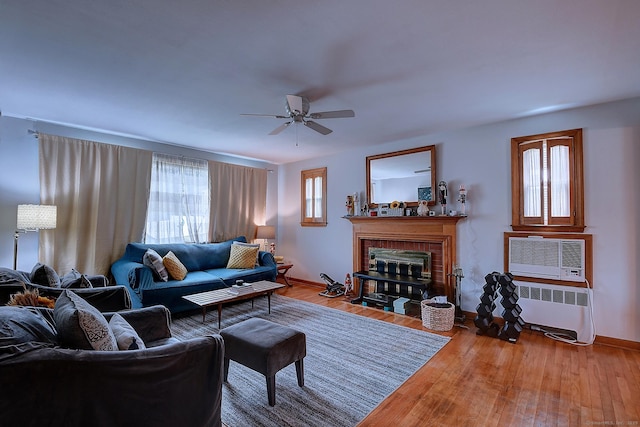 47 Hoffman Rd, Manchester, CT 06042 - living room with radiator, a ceiling fan, a fireplace, wood finished floors, and a wall unit AC