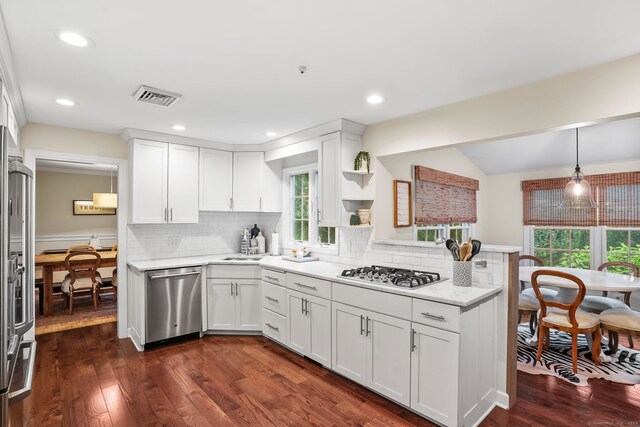112 Greenbrier Rd, Trumbull, CT 06611 - kitchen featuring appliances with stainless steel finishes, white cabinets, dark wood-style floors, decorative backsplash, and a peninsula