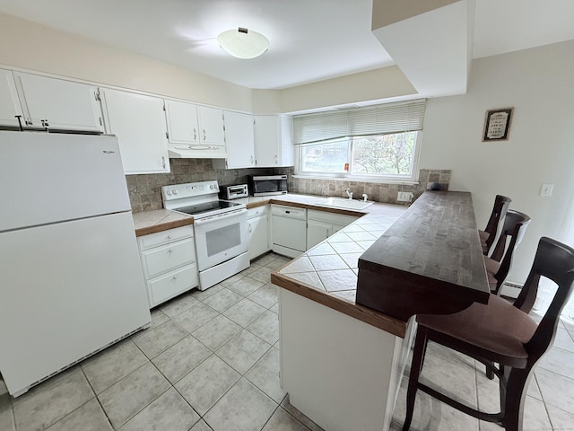 333 Vincellette St Unit 114, Bridgeport, CT 06606 - kitchen featuring white appliances, a peninsula, under cabinet range hood, and tile counters