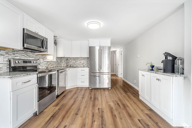1376 W St, Southington, CT 06489 - kitchen featuring stainless steel appliances, decorative backsplash, light wood-type flooring, light stone counters, and white cabinetry