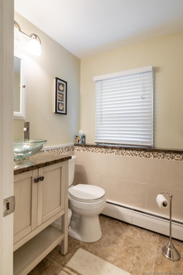 38 Evelyn Rd, Bristol, CT 06010 - bathroom featuring baseboard heating, vanity, tile walls, tile patterned floors, and a wainscoted wall