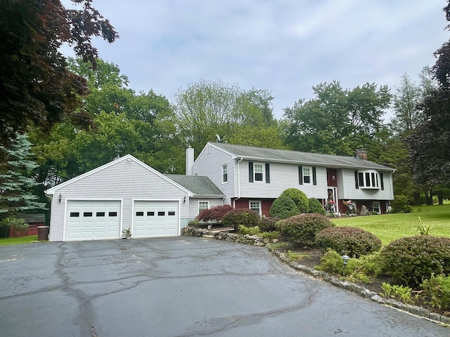 39 Mariner Cir, Trumbull, CT 06611 - bi-level home with a chimney, asphalt driveway, a front yard, and view of wooded area