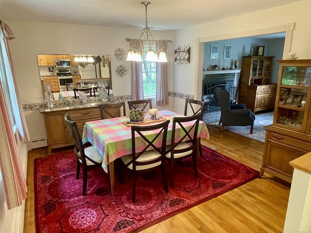 39 Mariner Cir, Trumbull, CT 06611 - dining room with light wood-type flooring, a chandelier, a baseboard radiator, and a fireplace