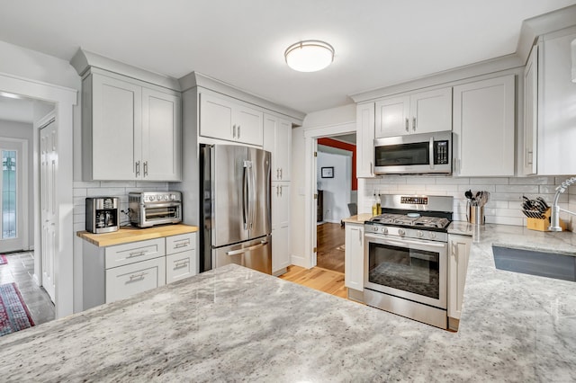 31 Stable Ridge Rd, Monroe, CT 06468 - kitchen featuring appliances with stainless steel finishes, decorative backsplash, light stone countertops, and light wood finished floors
