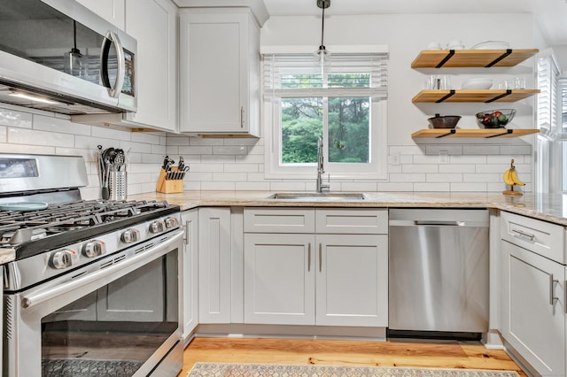 31 Stable Ridge Rd, Monroe, CT 06468 - kitchen featuring appliances with stainless steel finishes, light wood-style floors, light stone countertops, backsplash, and decorative light fixtures