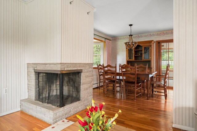 43 Dimmock Rd, Waterford, CT 06385 - dining space with wallpapered walls, wood finished floors, a baseboard heating unit, a chandelier, and a brick fireplace