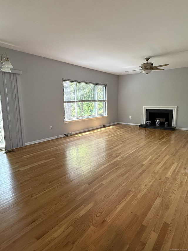 13 Hills Ln Unit 13, Norwalk, CT 06880 - unfurnished living room with wood finished floors, a fireplace with raised hearth, and a ceiling fan