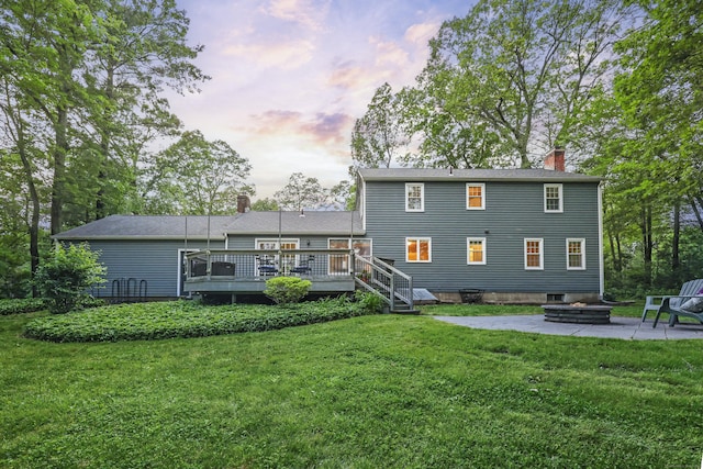 30 Clifdon Dr, Simsbury, CT 06070 - back of house at dusk with a wooden deck, a patio area, a chimney, and a lawn