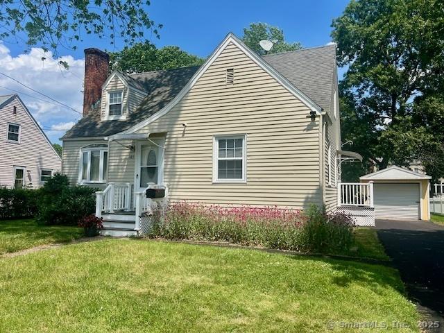 489 Adams St, Manchester, CT 06040 - view of front facade with a chimney, a garage, an outdoor structure, and a front lawn