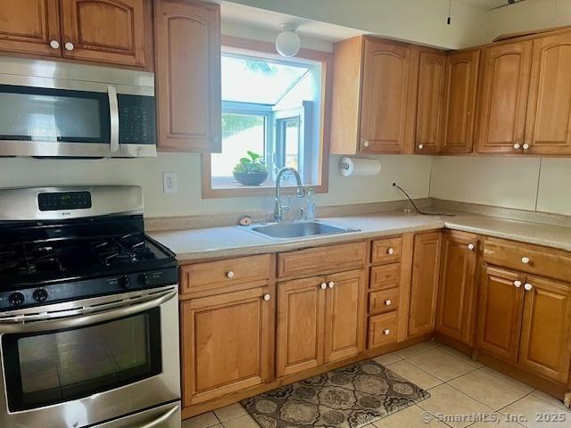 489 Adams St, Manchester, CT 06040 - kitchen with stainless steel appliances, light countertops, light tile patterned floors, and brown cabinets