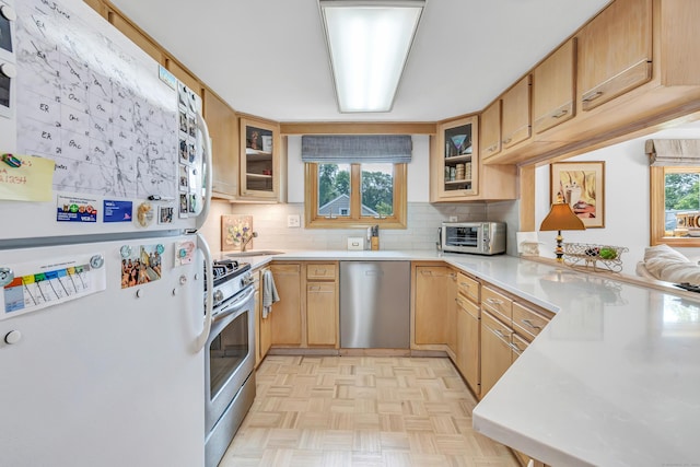 16 Senga Rd, Norwalk, CT 06854 - kitchen featuring appliances with stainless steel finishes, light countertops, decorative backsplash, and glass insert cabinets
