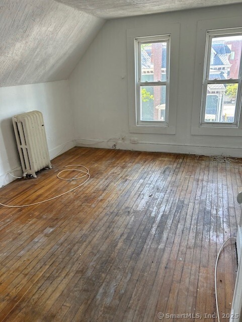 358 Orchard St, New Haven, CT 06511 - additional living space featuring radiator heating unit, hardwood / wood-style floors, and vaulted ceiling