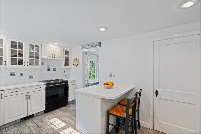 16 Lynde St, Old Saybrook, CT 06475 - kitchen with black / electric stove, a breakfast bar area, white cabinetry, a peninsula, and light countertops