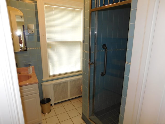 58 Edward St, East Haven, CT 06512 - bathroom with radiator heating unit, a stall shower, tile patterned floors, vanity, and tile walls