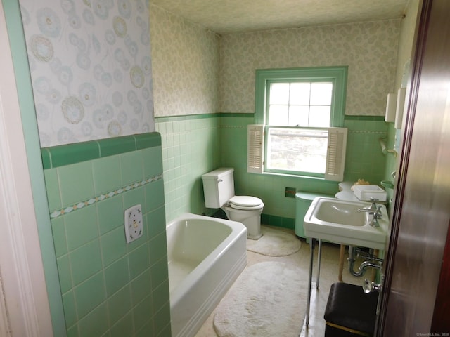 58 Edward St, East Haven, CT 06512 - bathroom with wallpapered walls, a bathtub, wainscoting, and tile walls
