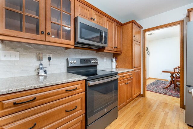 6 Old Sawmill Dr, Beacon Falls, CT 06403 - kitchen with stainless steel appliances, light wood-style floors, brown cabinetry, and decorative backsplash