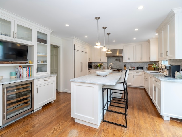 565 Danbury Rd, Wilton, CT 06897 - kitchen with wine cooler, extractor fan, paneled refrigerator, white cabinetry, and backsplash