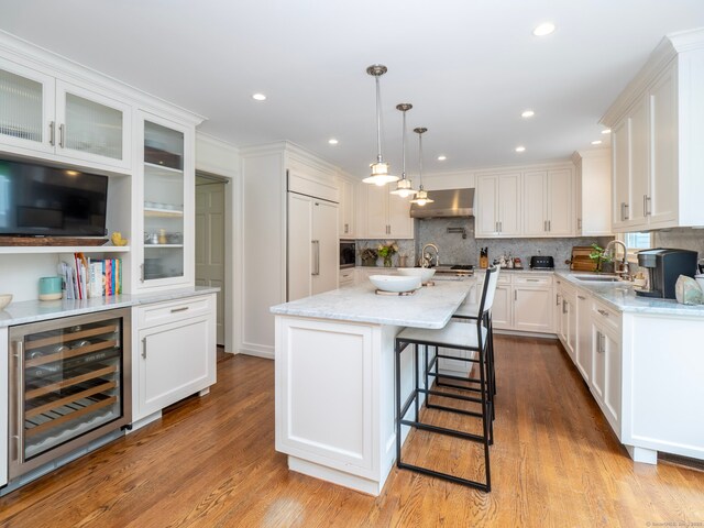 565 Danbury Rd, Wilton, CT 06897 - kitchen with wine cooler, range hood, paneled built in fridge, white cabinetry, and decorative backsplash