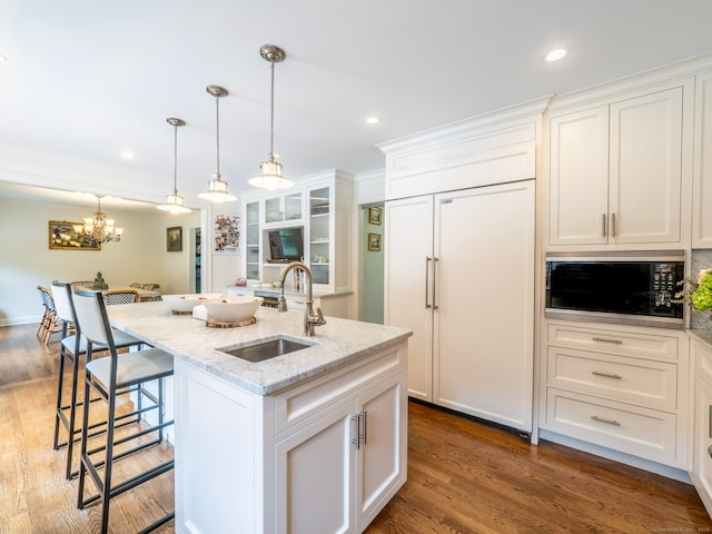 565 Danbury Rd, Wilton, CT 06897 - kitchen featuring built in appliances, white cabinets, a kitchen bar, light stone countertops, and a center island with sink