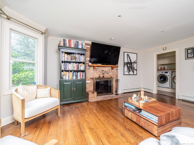 565 Danbury Rd, Wilton, CT 06897 - living area with washing machine and clothes dryer, a baseboard radiator, crown molding, a brick fireplace, and wood finished floors