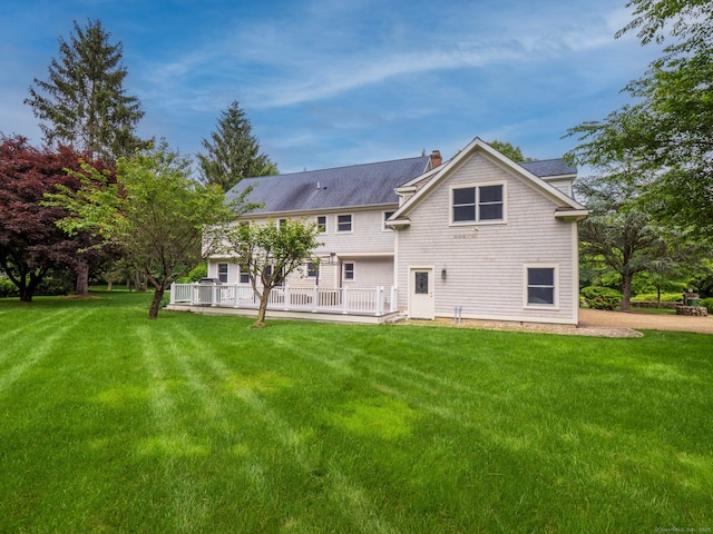 565 Danbury Rd, Wilton, CT 06897 - rear view of house with a chimney, a lawn, a wooden deck, and roof with shingles