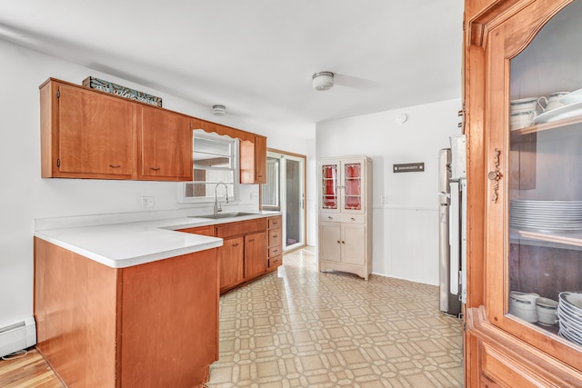 23 Laurel Wood Dr, Shelton, CT 06484 - kitchen featuring light flooring, a peninsula, baseboard heating, light countertops, and brown cabinetry
