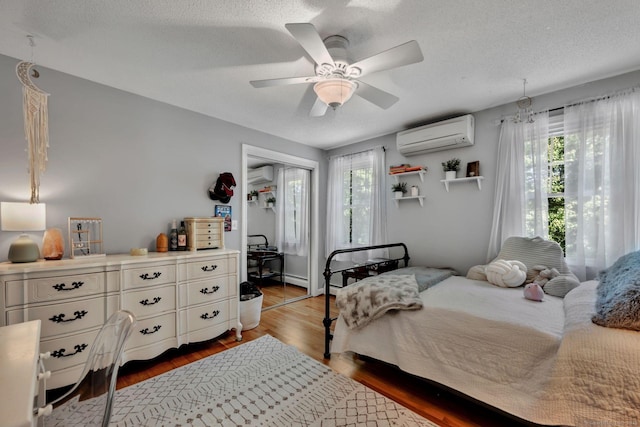 35 Twelve Acre Ln, Glastonbury, CT 06033 - bedroom with a wall mounted AC, a wall unit AC, wood finished floors, a textured ceiling, and a closet