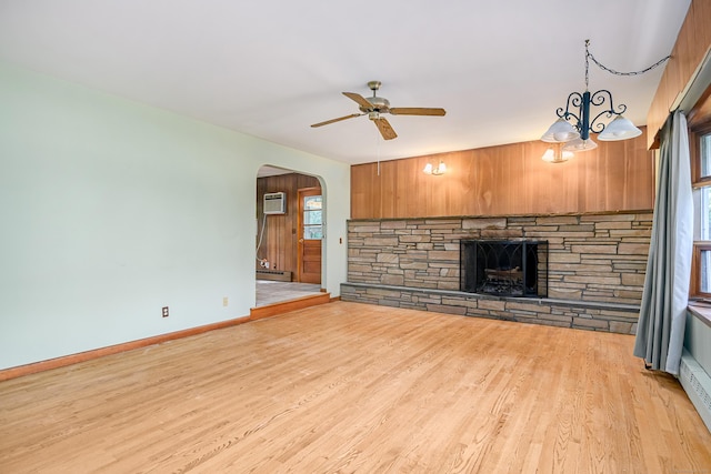 24 Warwick Rd, New Fairfield, CT 06812 - unfurnished living room with a stone fireplace, arched walkways, ceiling fan, light wood-style floors, and a wall mounted air conditioner