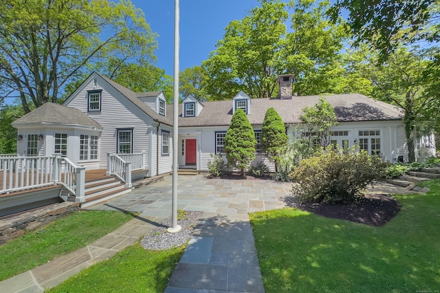 182 Bennetts Farm Rd, Ridgefield, CT 06877 - new england style home with a deck, a patio area, a chimney, a front lawn, and a shingled roof