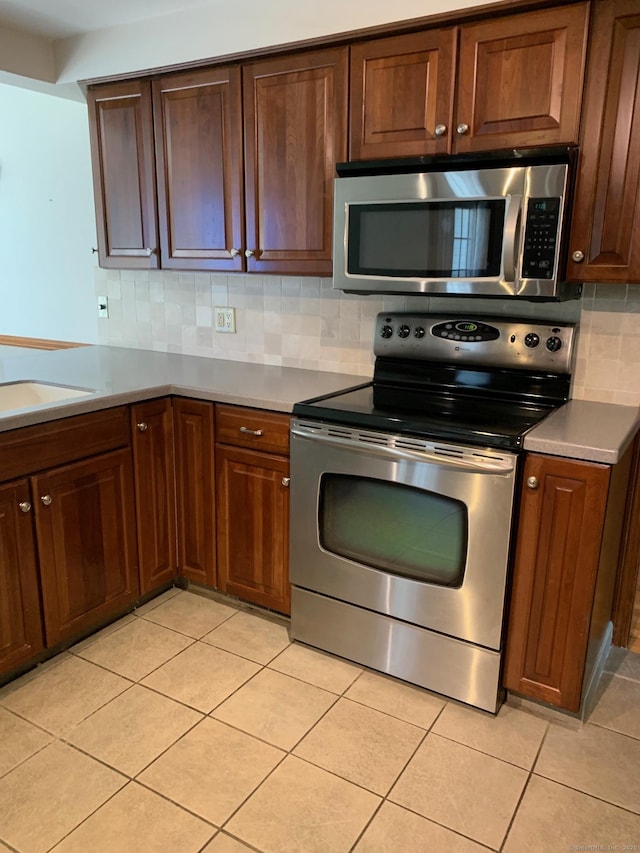 180 Round Hill Rd, Cheshire, CT 06410 - kitchen featuring appliances with stainless steel finishes, decorative backsplash, light tile patterned floors, and light countertops