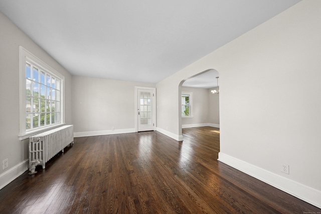 42 Marlboro St, Waterbury, CT 06705 - empty room with radiator heating unit, plenty of natural light, arched walkways, and dark wood-style floors