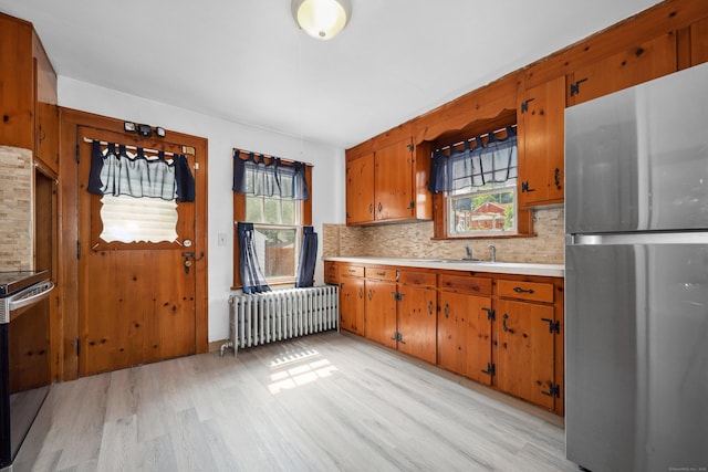 42 Marlboro St, Waterbury, CT 06705 - kitchen featuring freestanding refrigerator, radiator heating unit, light wood-style flooring, light countertops, and tasteful backsplash