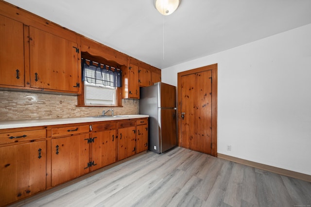 42 Marlboro St, Waterbury, CT 06705 - kitchen featuring freestanding refrigerator, light wood-type flooring, light countertops, decorative backsplash, and brown cabinetry