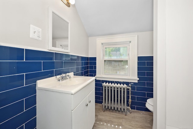 42 Marlboro St, Waterbury, CT 06705 - bathroom with tile walls, radiator, vanity, lofted ceiling, and wood finished floors