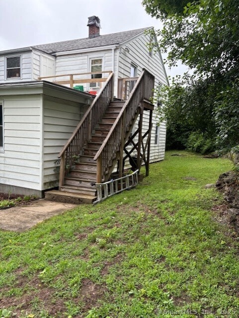 31 Happy St, Norwich, CT 06360 - rear view of property featuring stairway, a lawn, a chimney, and roof with shingles