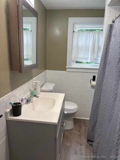 31 Happy St, Norwich, CT 06360 - full bath with tile walls, wood finished floors, vanity, wainscoting, and a shower with shower curtain