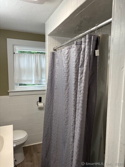 31 Happy St, Norwich, CT 06360 - bathroom with wood finished floors, vanity, a shower with shower curtain, tile walls, and a textured ceiling