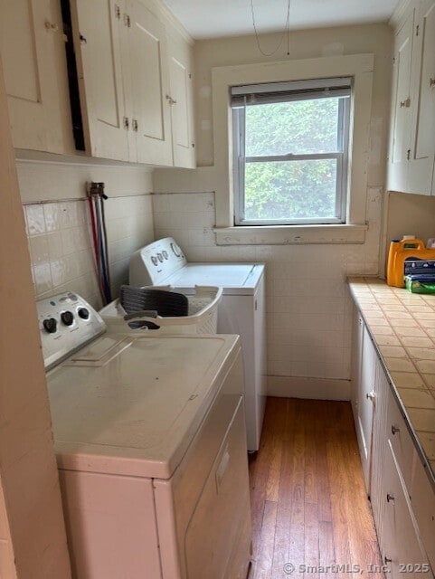 31 Happy St, Norwich, CT 06360 - laundry room featuring washing machine and dryer, cabinet space, and light wood-style floors