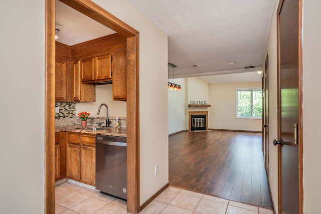 80 Copper Beech Dr Unit 80, Rocky Hill, CT 06067 - kitchen with dishwasher, brown cabinets, light stone counters, open floor plan, and a glass covered fireplace