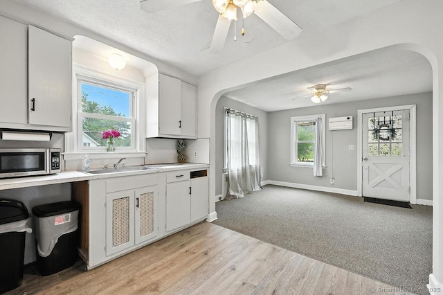 85 Peck St, Berlin, CT 06037 - kitchen featuring stainless steel microwave, a ceiling fan, arched walkways, a wall unit AC, and light countertops