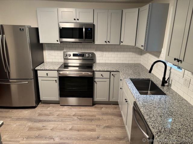 56 Cedar Swamp Rd, Mansfield, CT 06268 - kitchen featuring stainless steel appliances, light wood finished floors, light stone countertops, and decorative backsplash