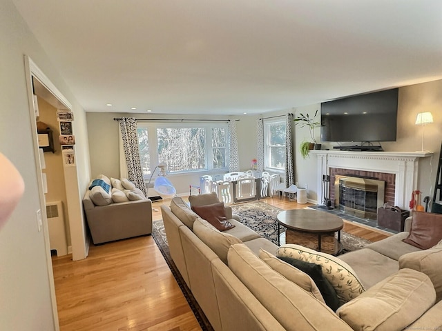 4380 Whitney Ave, Hamden, CT 06518 - living room featuring light wood-style floors, radiator heating unit, a brick fireplace, and recessed lighting