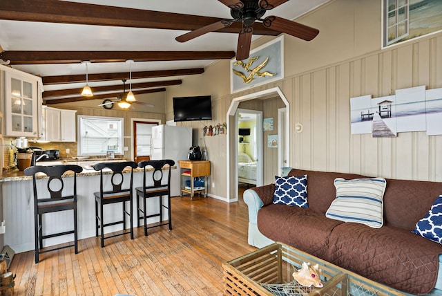 living area featuring ceiling fan, light wood-style floors, and arched walkways